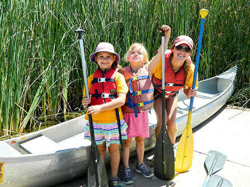 Campers posing with the counselor and canoe