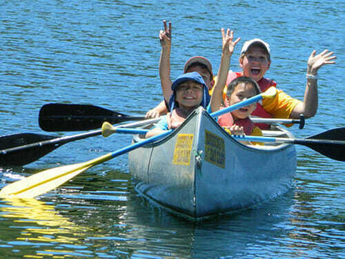 Campers waving to the camera from their canoe