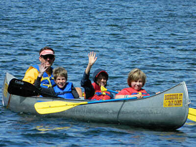 Teen Campers Wave from a Canoe