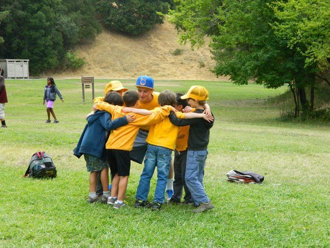 young boy campers huddle with team at roughing it day camp at the lafayette reservoir with counselor