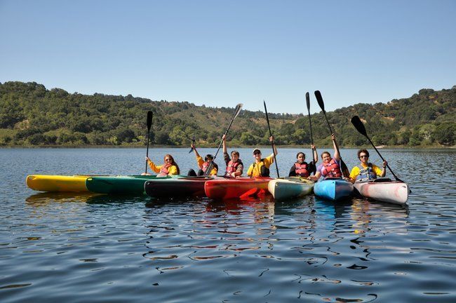 teen campers and counselros at Roughing It day camp smiling in kayaks together at the lafayette reservoir