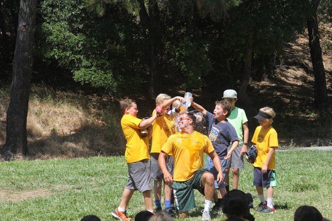 boy campers pouring water on their counselor at roughing it day camp for skit at the lafayette reservoir