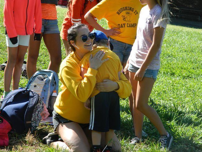 counselor at roughing it day camp hugging young camper at lafayette reservoir