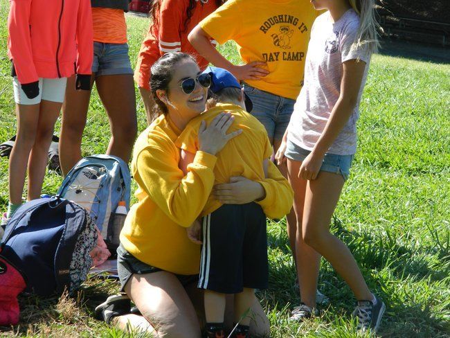 counselor at roughing it day camp hugging young camper at lafayette reservoir