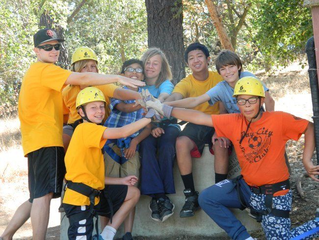 campers and counselor at roughing it day camp in teamwork huddle before beginning rock climbing