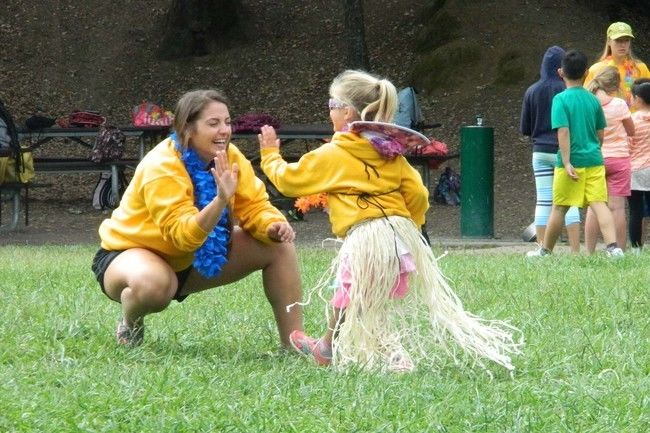 camper and counselor at roughing it day camp high fiving at the lafayette reservoir, dressed up for hawaii day